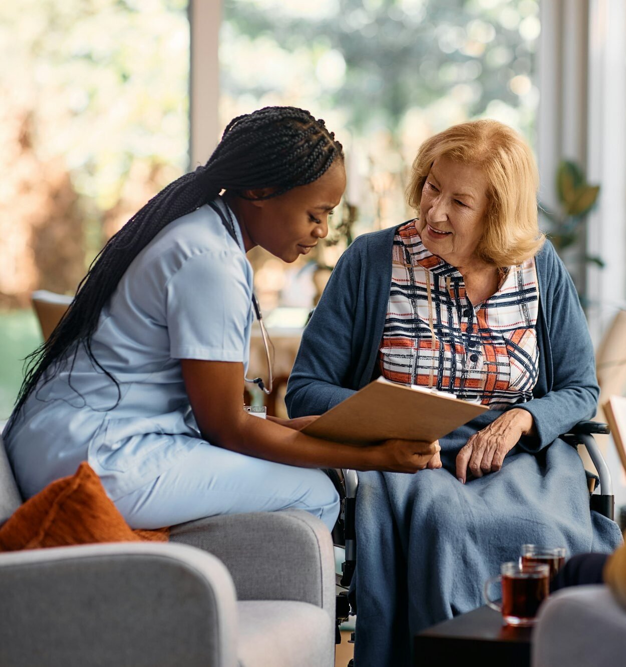 Happy senior woman going through her medical data with young nurse at residential care home.